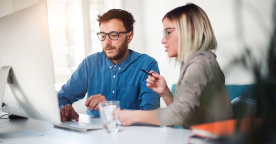 Duas pessoas a examinar dados num computador 