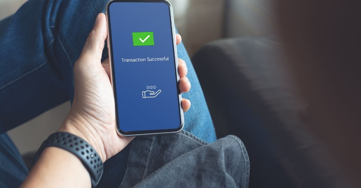 Um homem a ver a sua transação bem sucedida no seu smartphone 